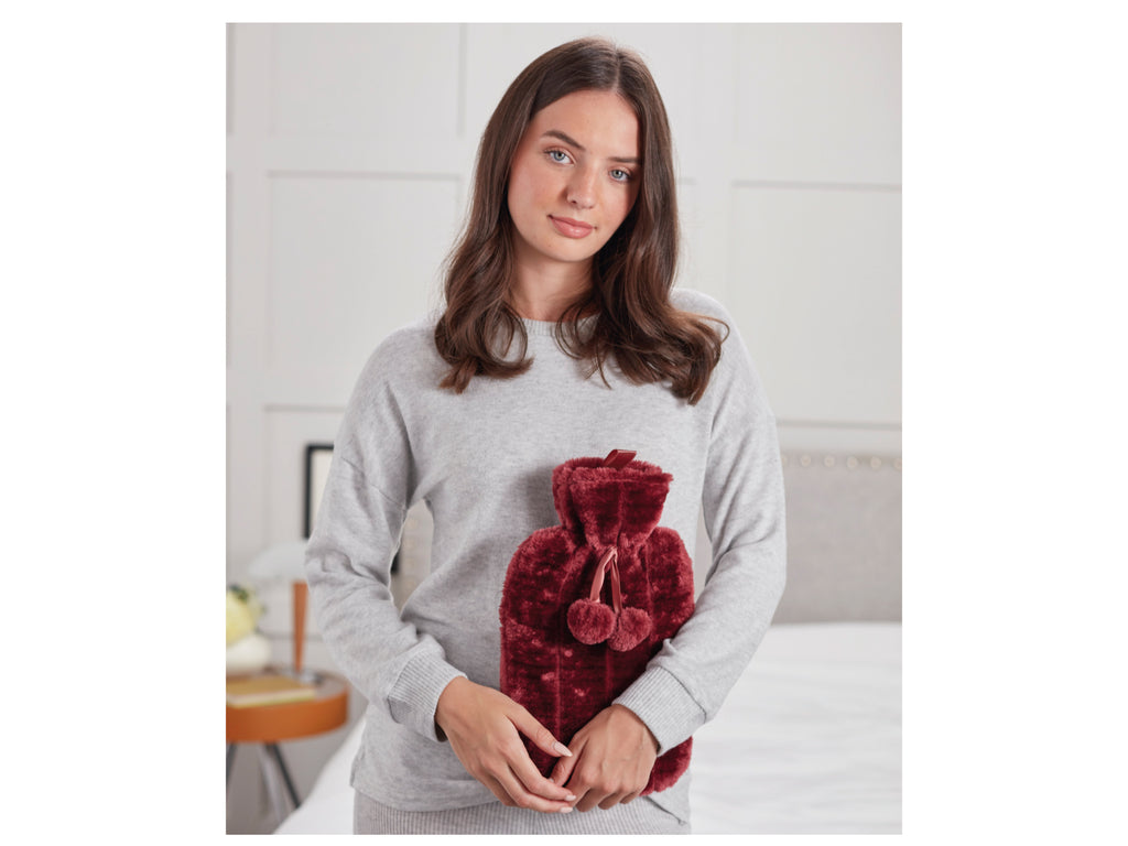 Woman carrying hot water bottle with plush cover in red